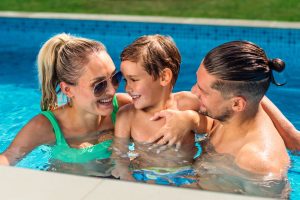 Happy parents holding their smiling son while swimming in the pool